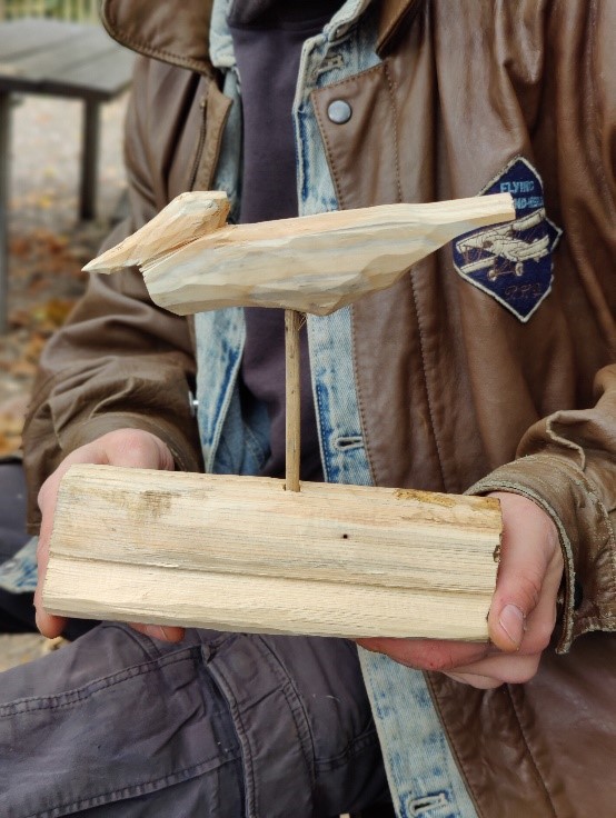 Eine Person hält eine Holzschnitzerei in den Händen