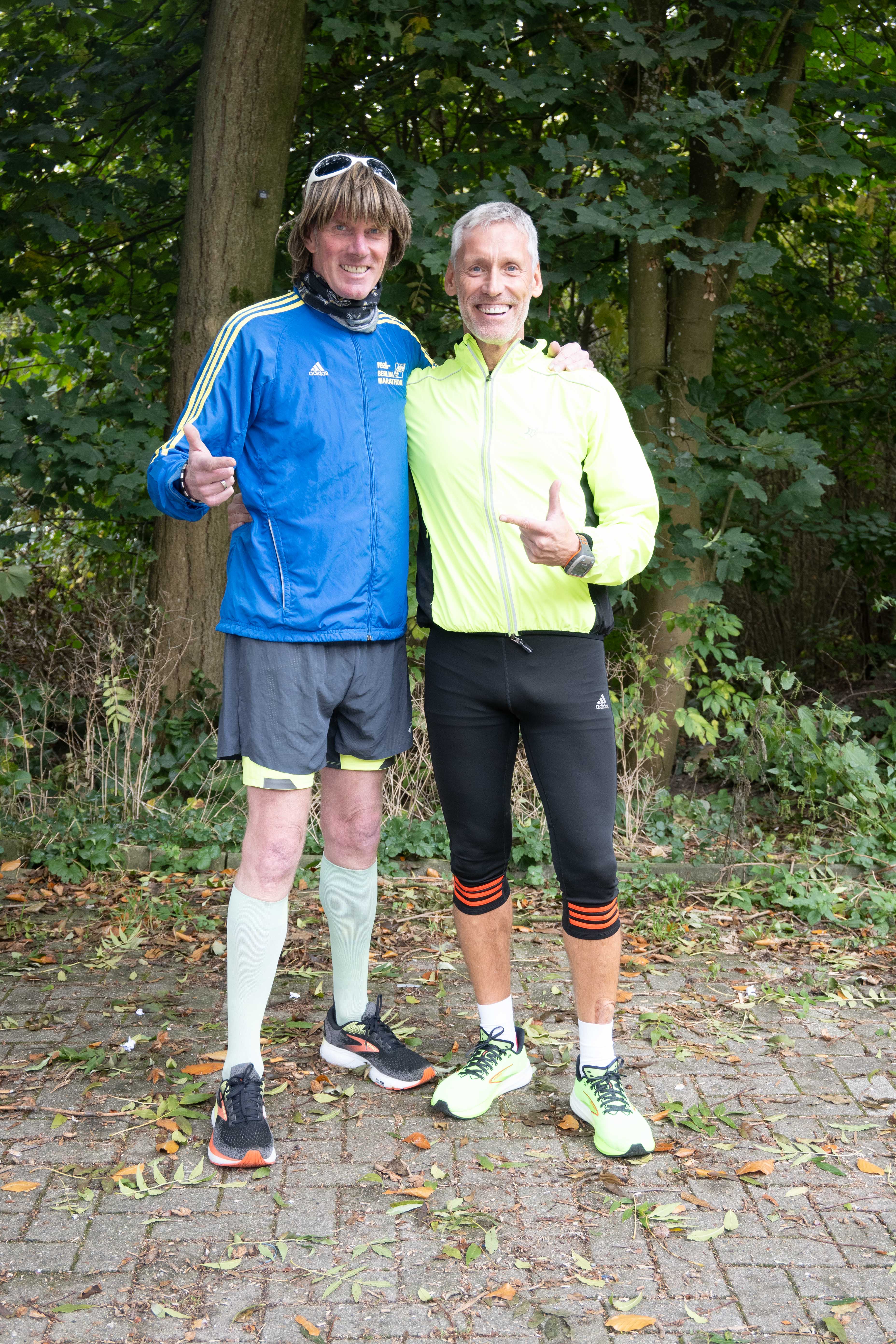 Zwei Männer in Sportkleidung stehen nebeneinander. Sie lächeln, einer hält den rechten Daumen nach oben.