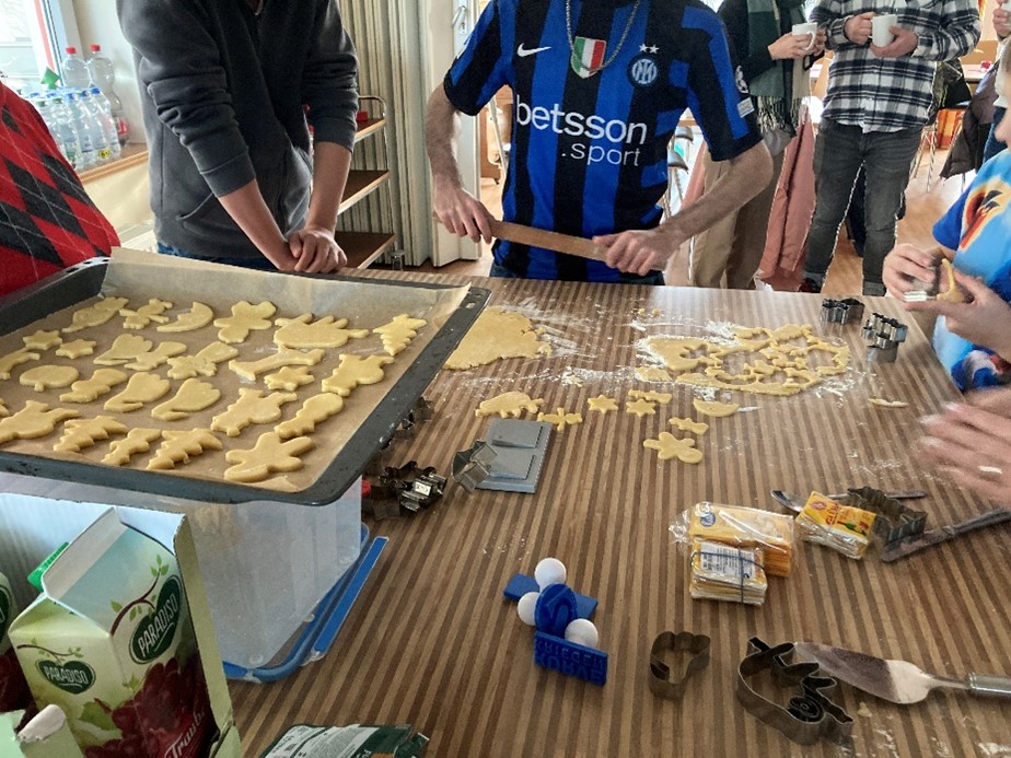 An einem Tisch bereiten verschiedene Personen Plätzchen zum Backen vor